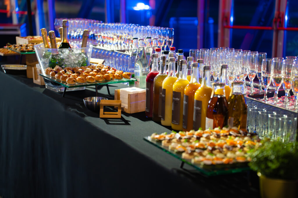 Buffet-bar de réception: bouteilles sous glace, jus colorés, nombreux verres à champagne et amuse-bouches sur le comptoir.