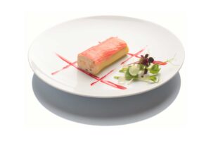 Roulé de saumon rose sur assiette blanche, sauce rouge et micro-pousses.