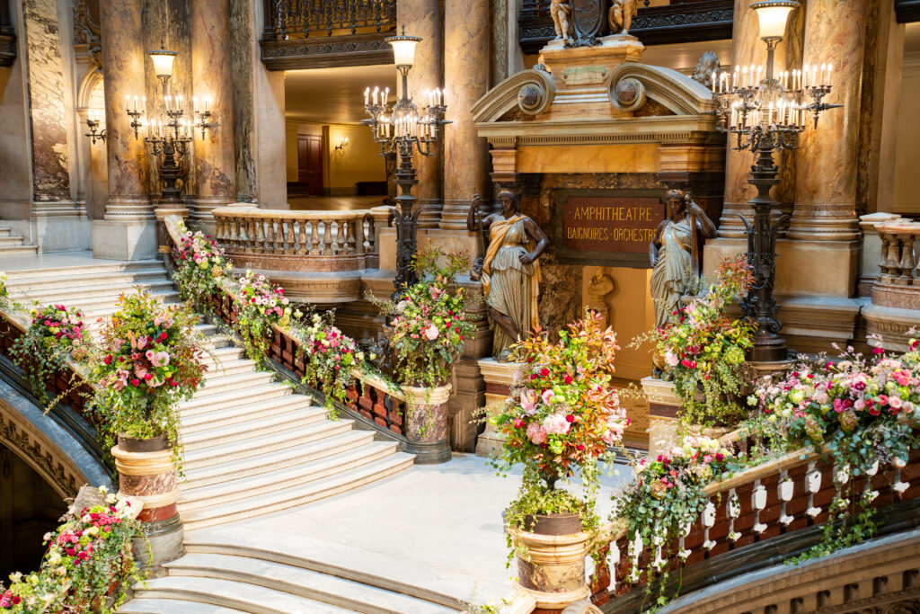 Entrée de l'amphithéâtre somptueusement décoré: marbre, colonnes, lustres, statues et fleurs.