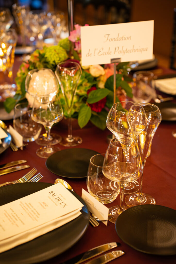 Table de banquet décorée avec bouquet, pancarte Fondation de l'École Polytechnique, menus et verres.