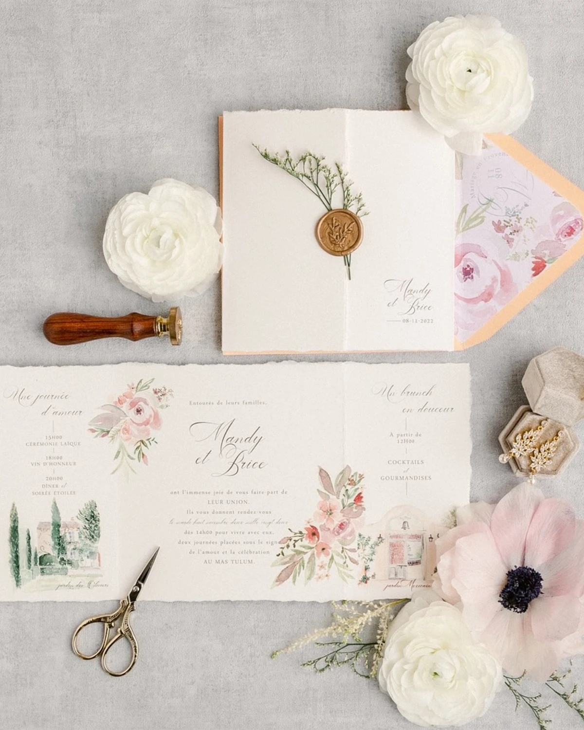 Invitation de mariage pastel avec sceau en cire, fleurs blanches et motifs floraux élégants.
