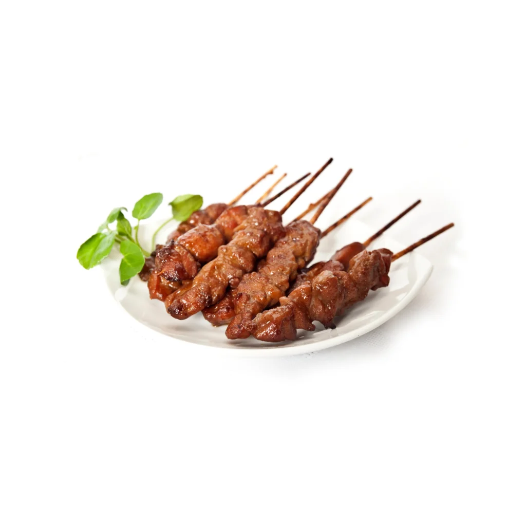 Brochettes de viande grillée sur assiette blanche, garnies de feuilles de menthe fraîche.