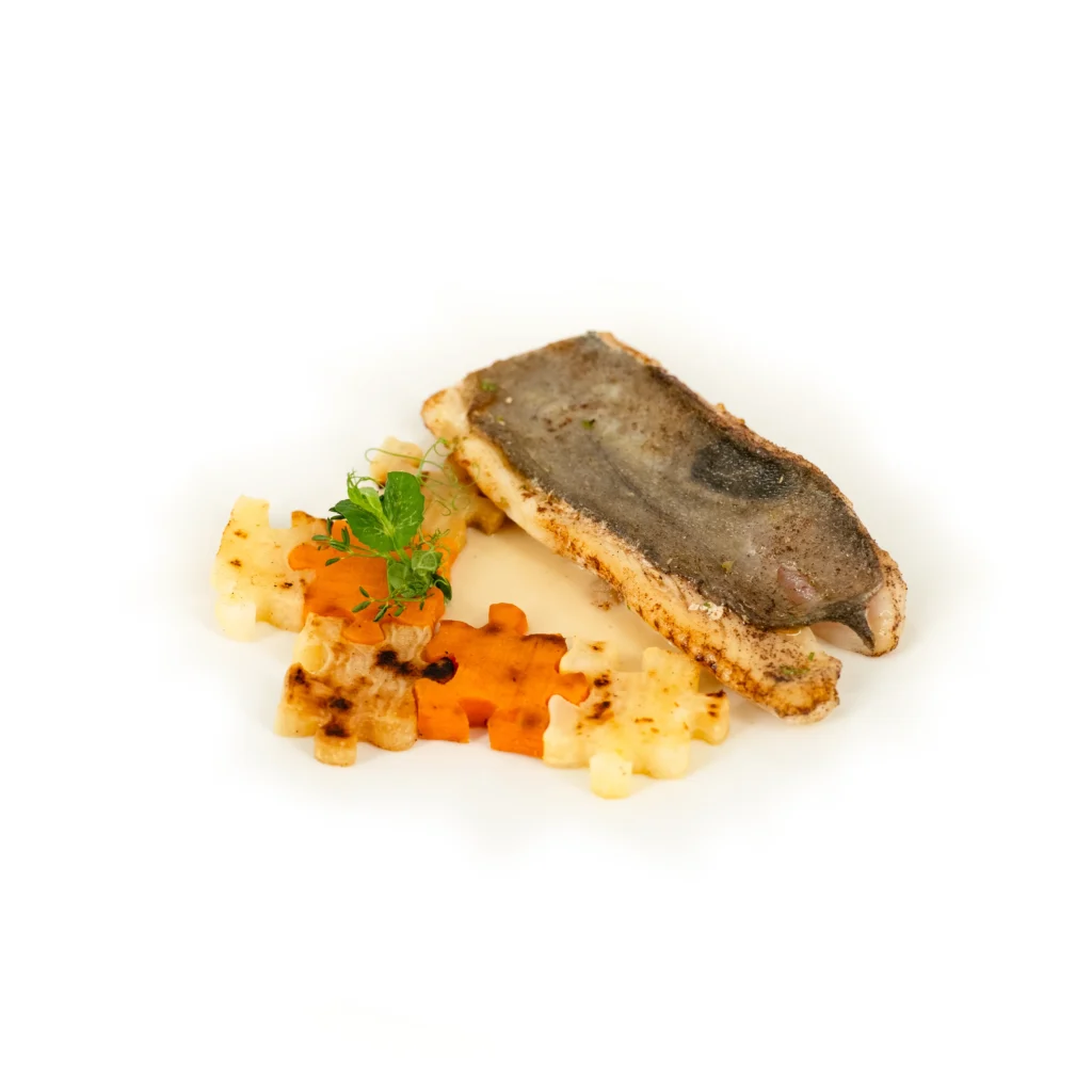Filet de poisson à peau croustillante, légumes et herbes fraîches en accompagnement.