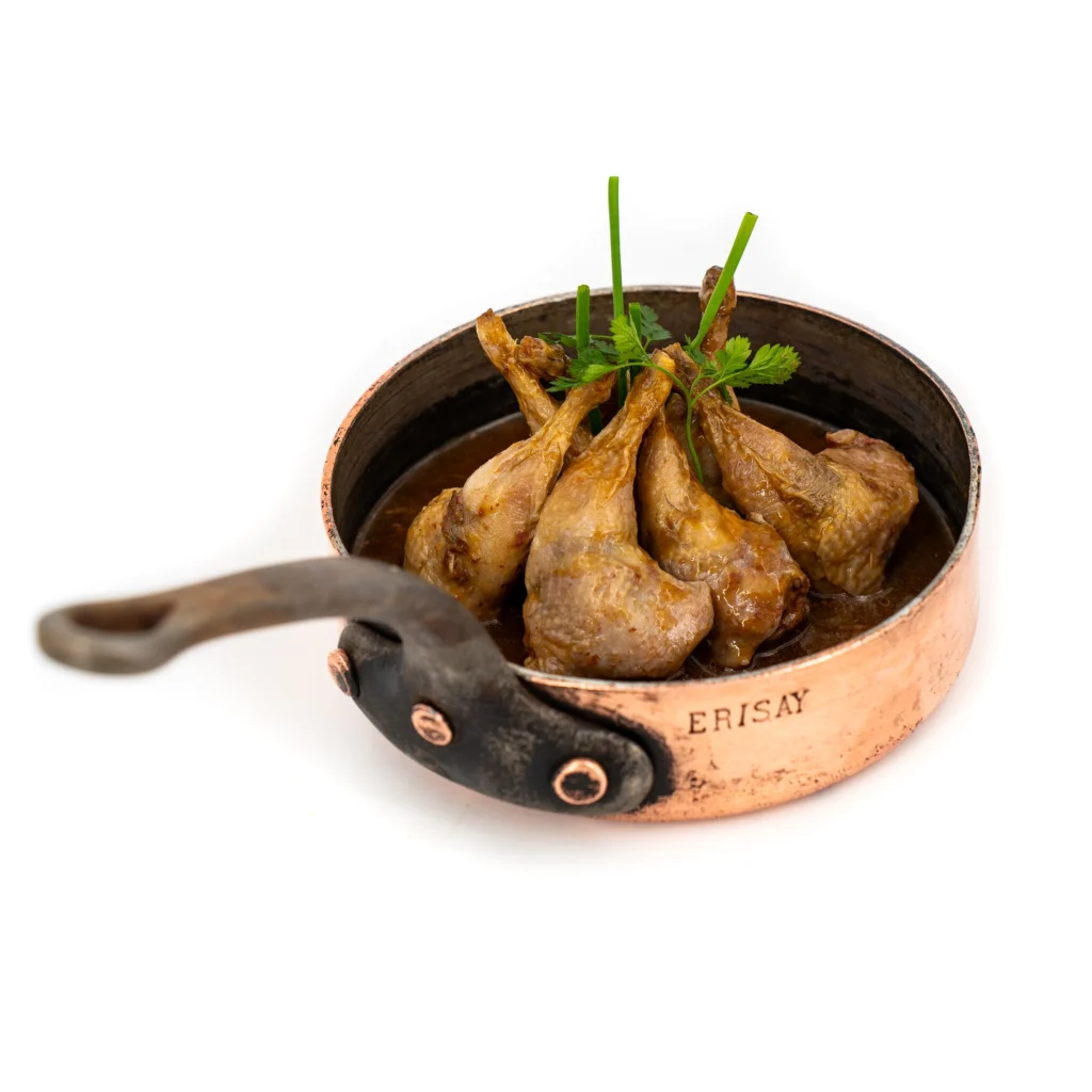 Morceaux de viande braisée dans une marmite en cuivre, garnis de ciboulette et de persil frais.