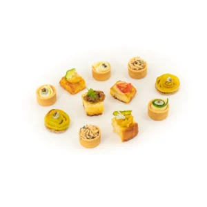Assortiment de mini canapés apéritifs garnis de légumes et crèmes sur assiette blanche.