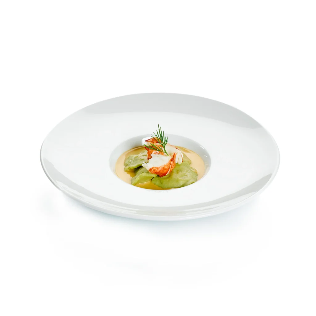 Plat gastronomique de homard sur purée verte et sauce orange, garniture d’aneth, servi sur une grande assiette blanche.