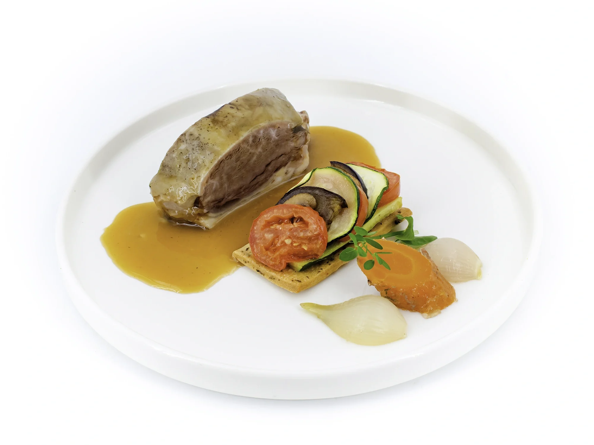 Pavé de viande nappé d'une sauce orange, accompagné de légumes colorés (courgette, tomate, carotte) sur assiette blanche.